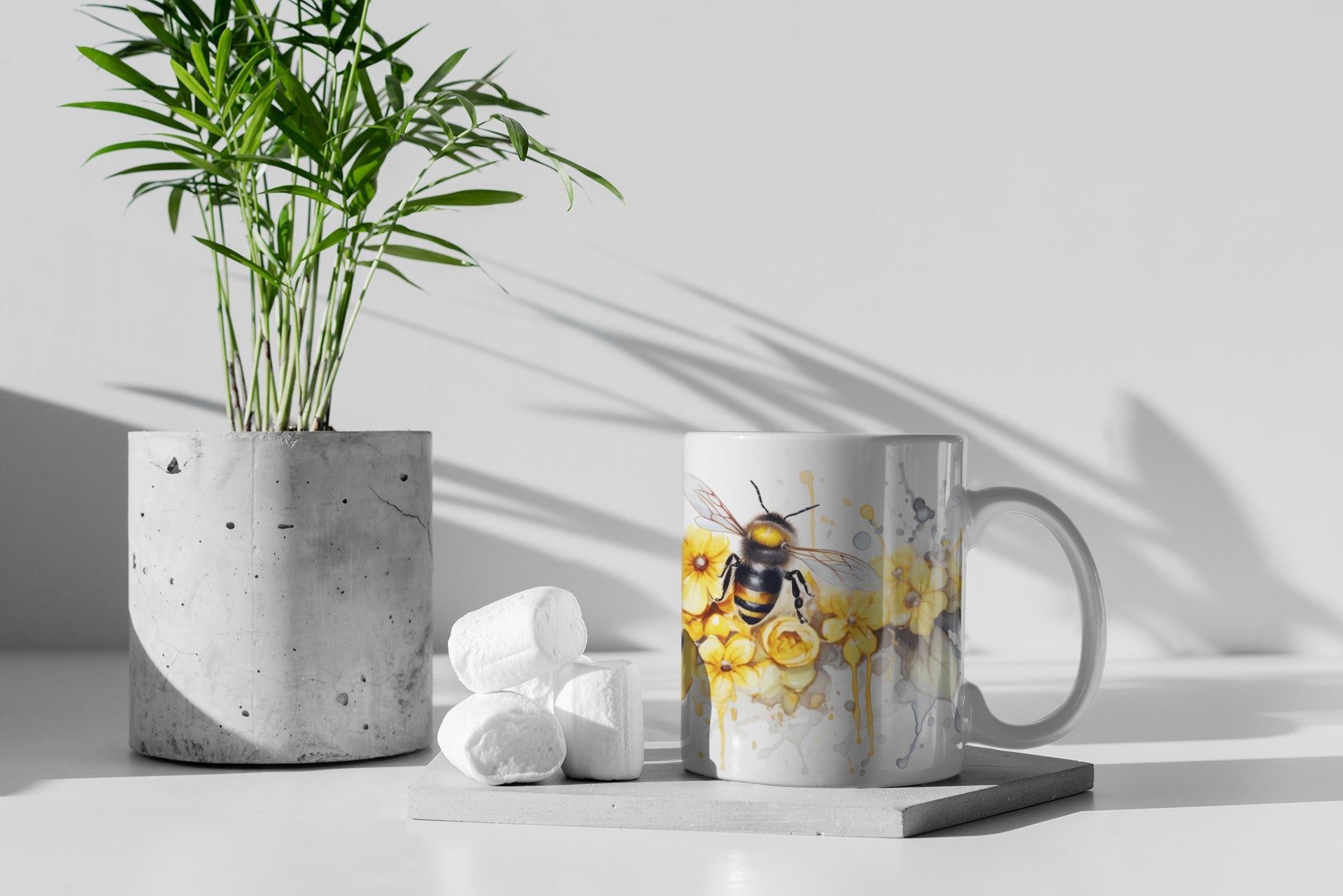 Mug with a bee design on a white surface with a plant and cotton balls.