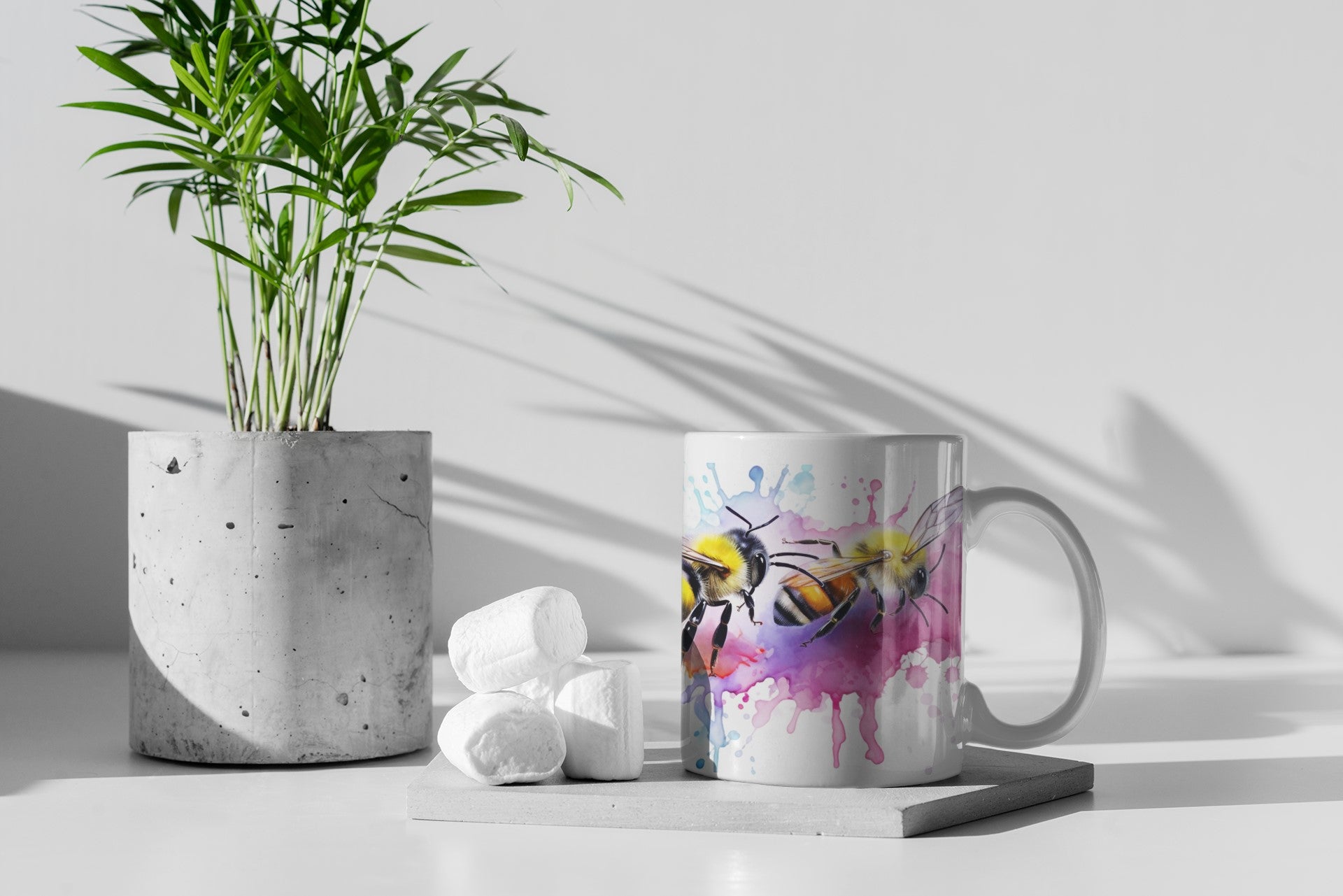 Mug with colorful design on a white surface with a plant and decorative items.