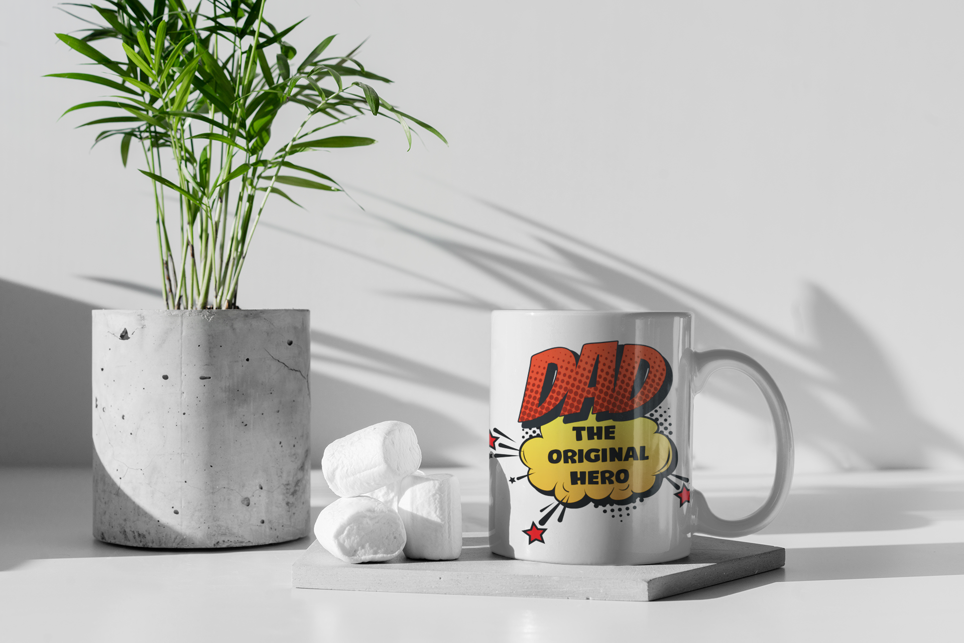 Mug with 'DAD THE ORIGINAL HERO' design on a white surface with a plant and decorative items.
