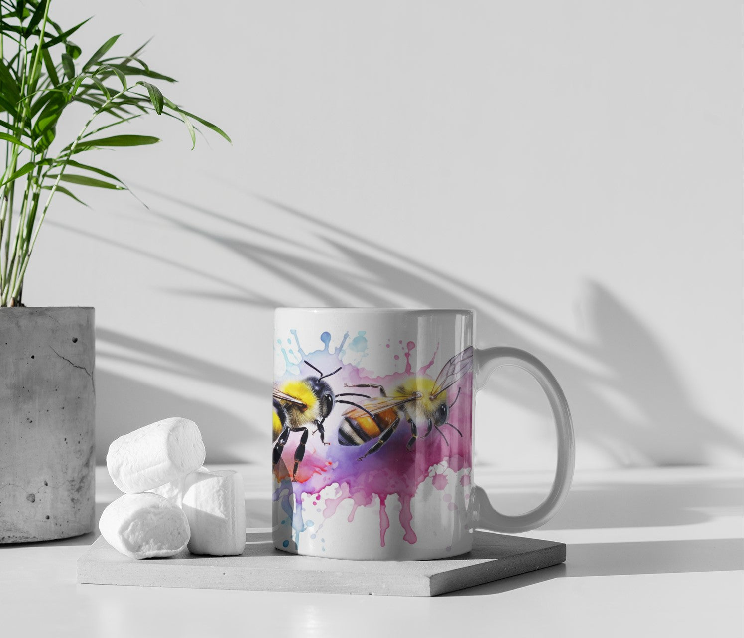 Mug with bee design on a light surface with a plant and marshmallows in the background