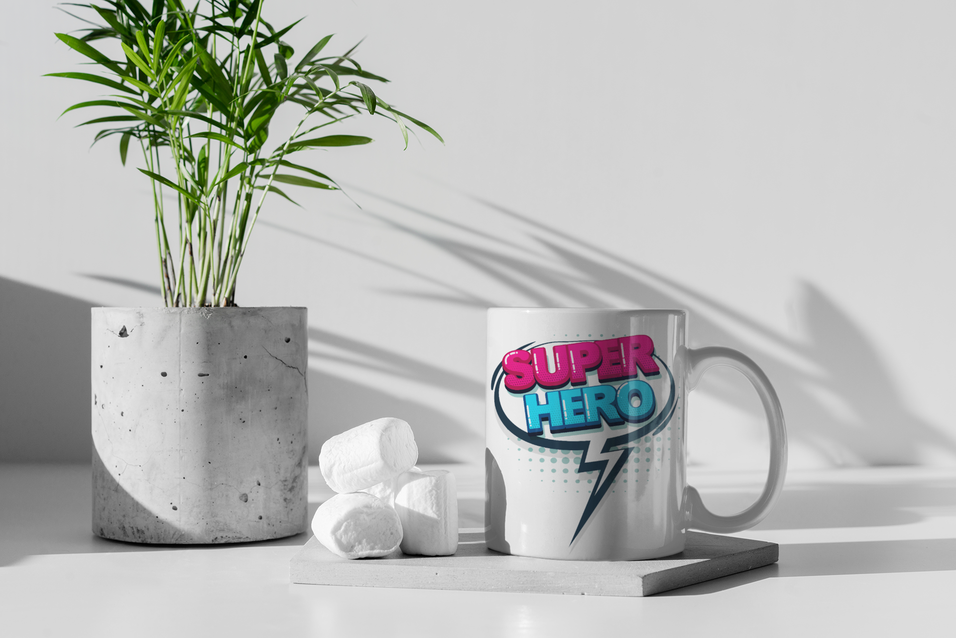 White mug with 'Super Hero' design on a white surface with a plant and books in the background