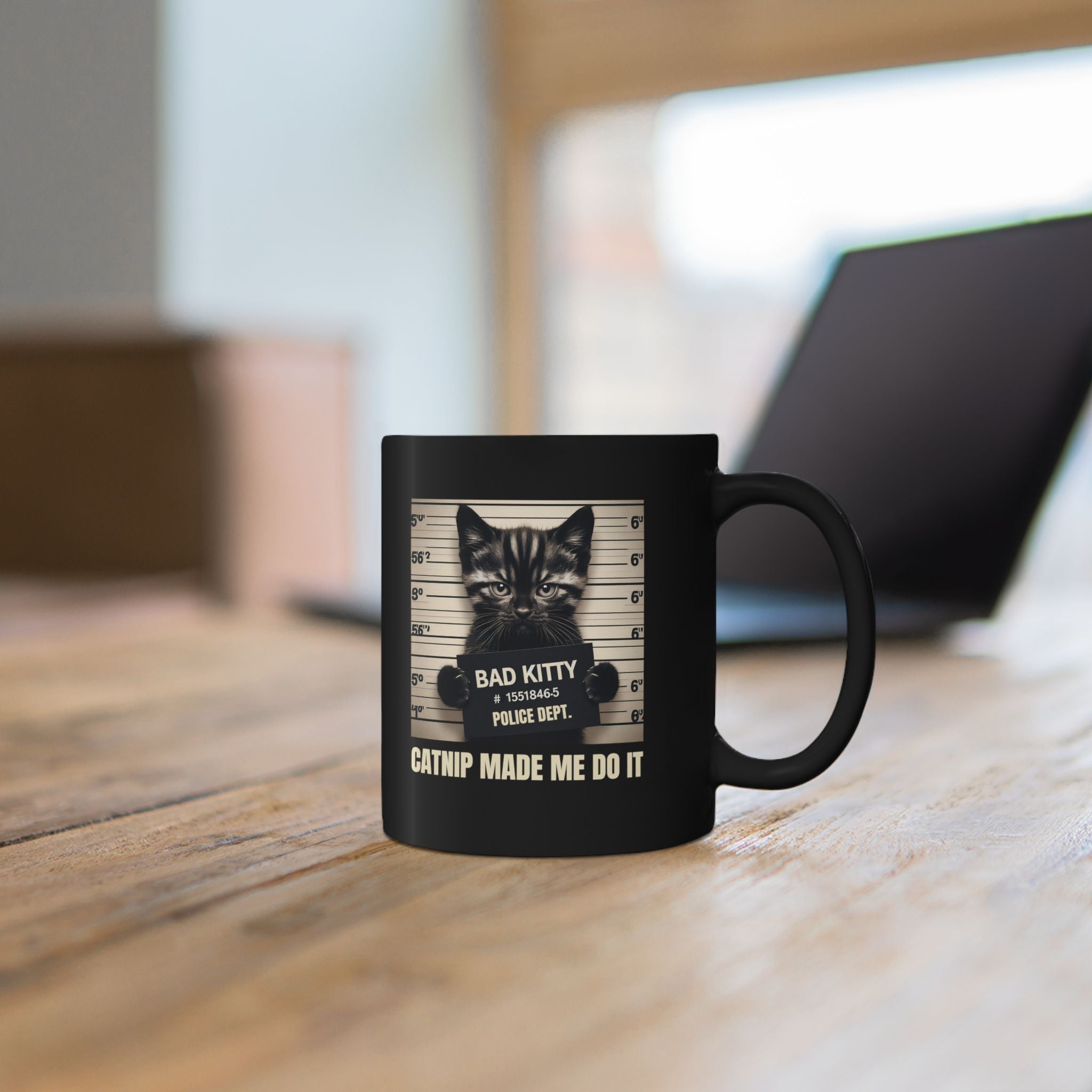 Black mug with a cat graphic and text on a wooden surface