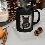 Black mug with a cat graphic and text, surrounded by decorative items on a table.