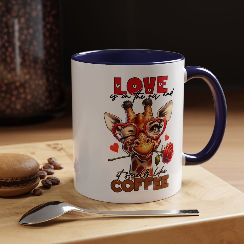 Mug with giraffe design and text 'Love is in the air and it smells like coffee' on a wooden surface with coffee beans and a spoon.