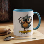Mug with cartoon owl design and text on a wooden surface with coffee beans and a macaron.