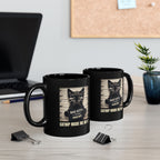 Two black mugs with cat-themed designs on a desk with office items.
