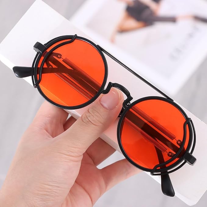 Round sunglasses with orange lenses and black frames held by a hand on a light background
