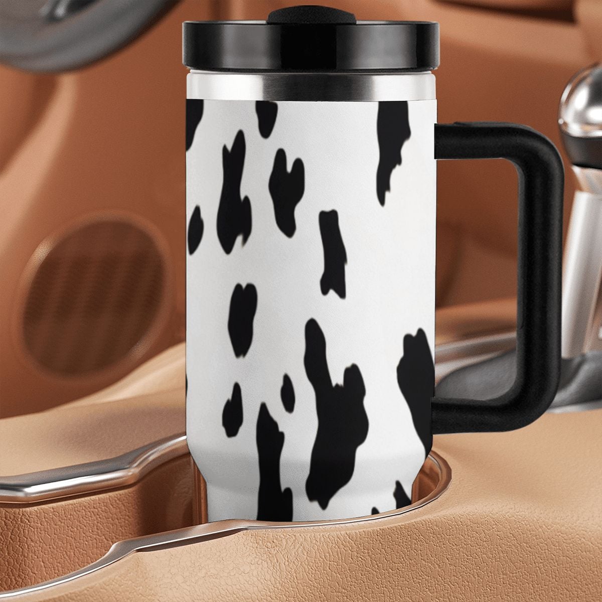 Travel mug with cow print design on a car seat