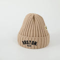 Beige knit beanie with 'Boston, 1630' text on a light gray background
