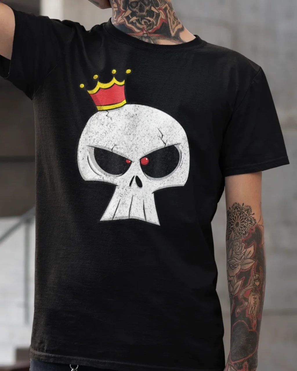 Black t-shirt with a skull design wearing a crown, worn by a person with tattoos.