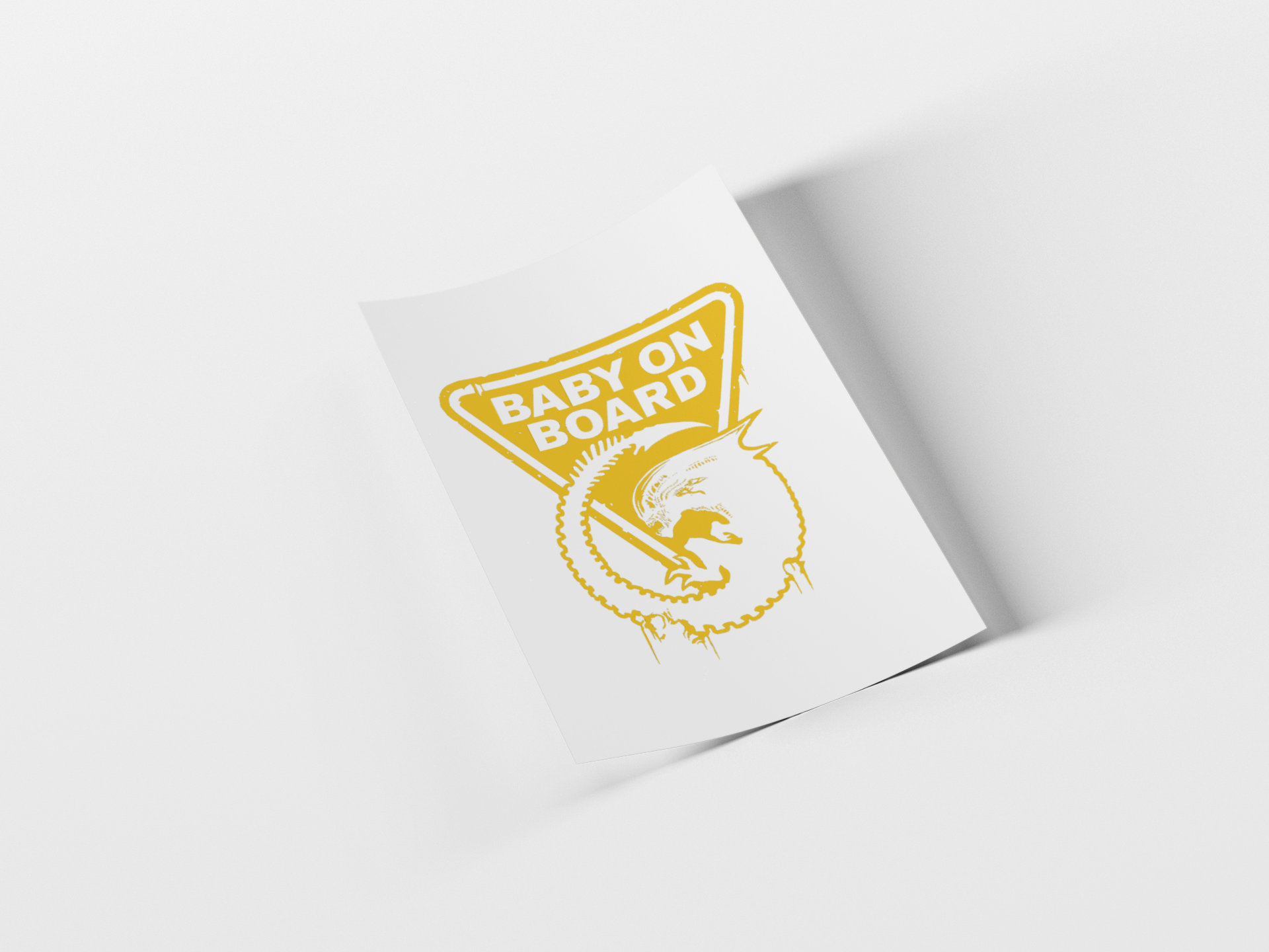 A white rectangular card or sticker with a yellow 'BABY ON BOARD' graphic and a stylized baby illustration, shown standing at an angle on a light gray background.