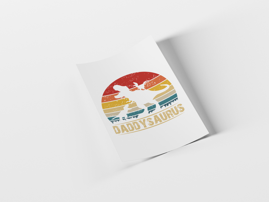 A white rectangular print or card shown at an angle on a light gray background, featuring a retro sunset-style graphic with a dinosaur silhouette and the text 'DADDYSAUROS'.