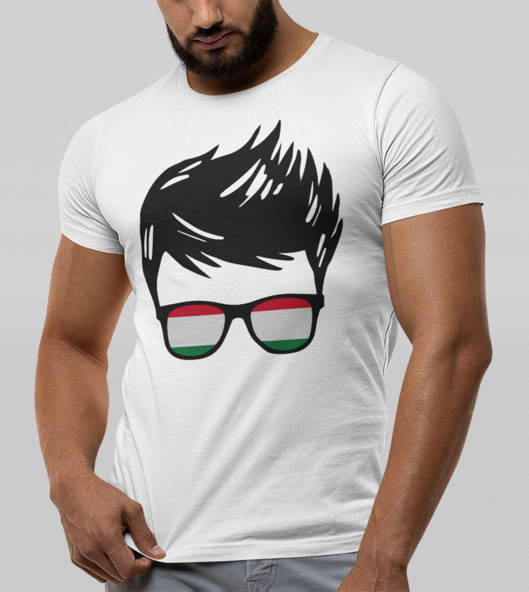 A man wearing a white short-sleeve t-shirt with a graphic print of a stylized black-haired man wearing glasses with the Hungarian flag colors (red, white, green) on the lenses, set against a solid gray background.