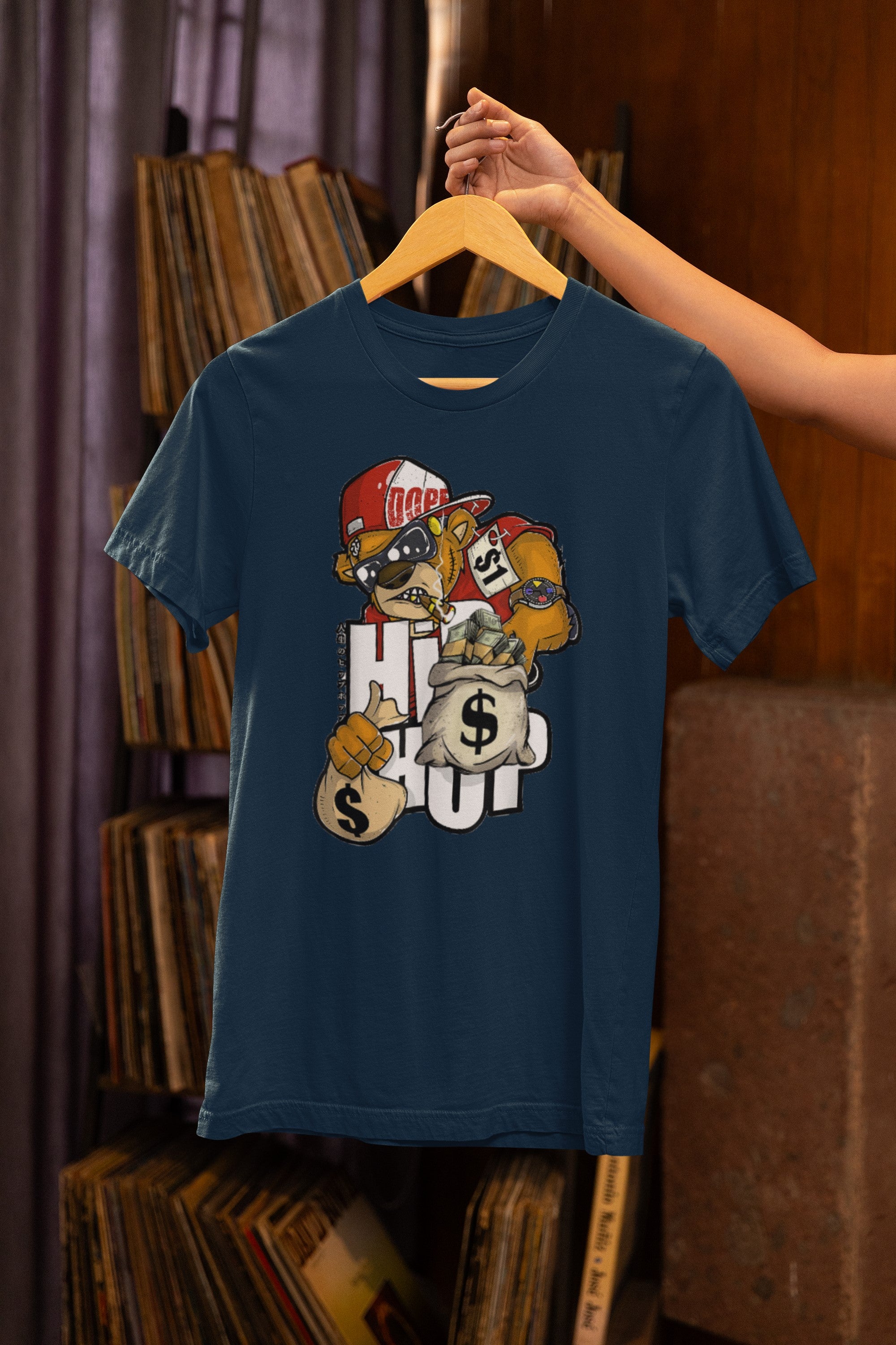 Navy blue t-shirt with a graphic design on a hanger against a bookshelf background