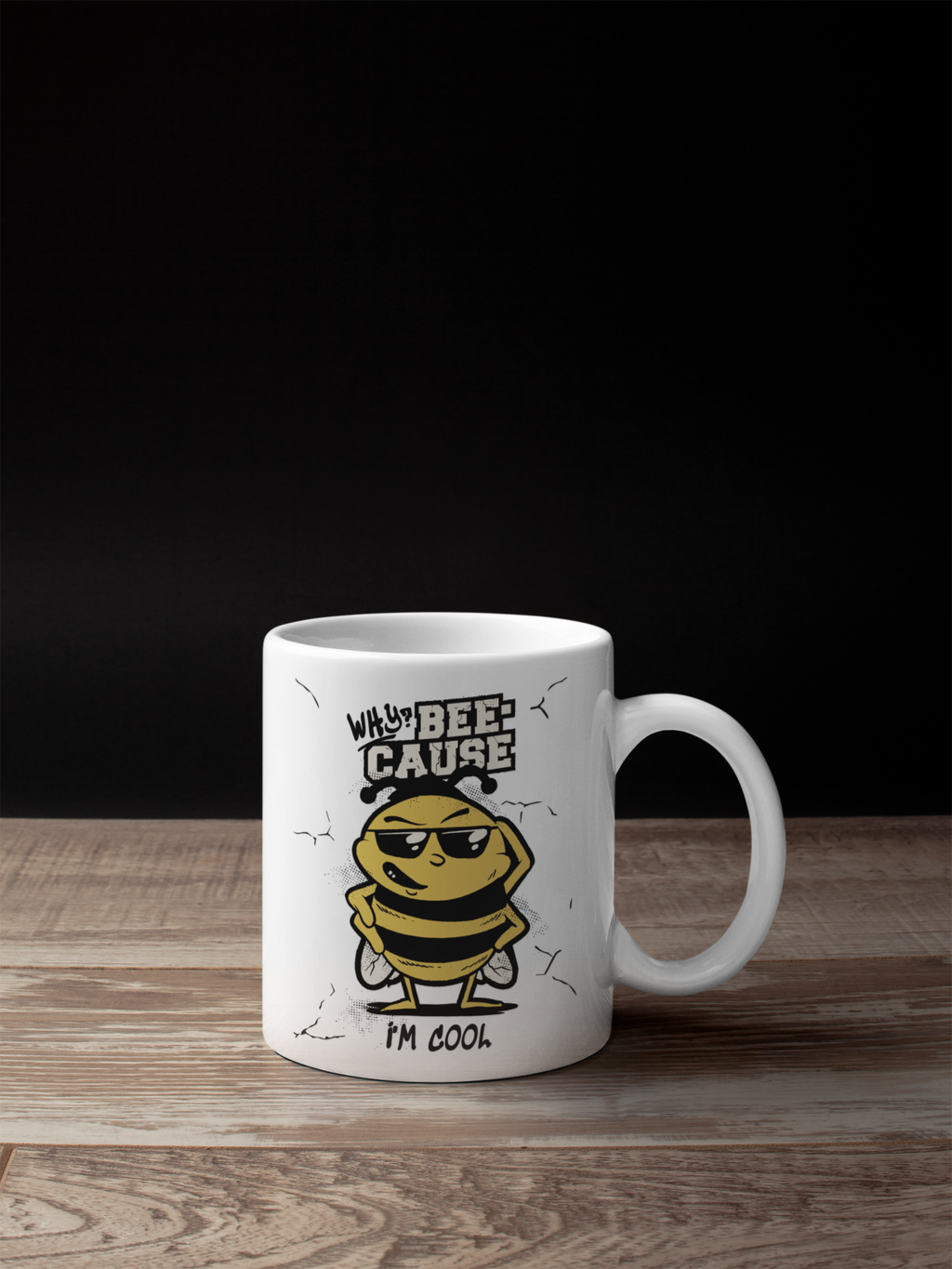 A white ceramic coffee mug with a cartoon bee graphic and the text 'WHY THE BEE-CAUSE I'M COOL' printed on the side, set on a wooden surface against a black background.