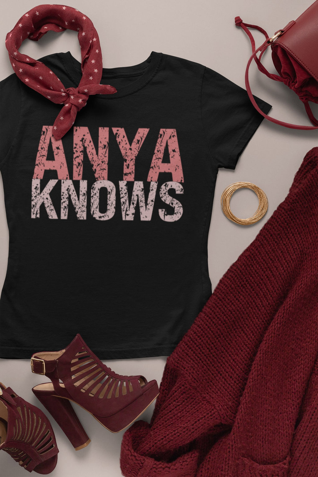 Black t-shirt with 'ANYA KNOWS' text, surrounded by red accessories on a light background