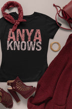 Black t-shirt with 'ANYA KNOWS' text, surrounded by red accessories on a light background