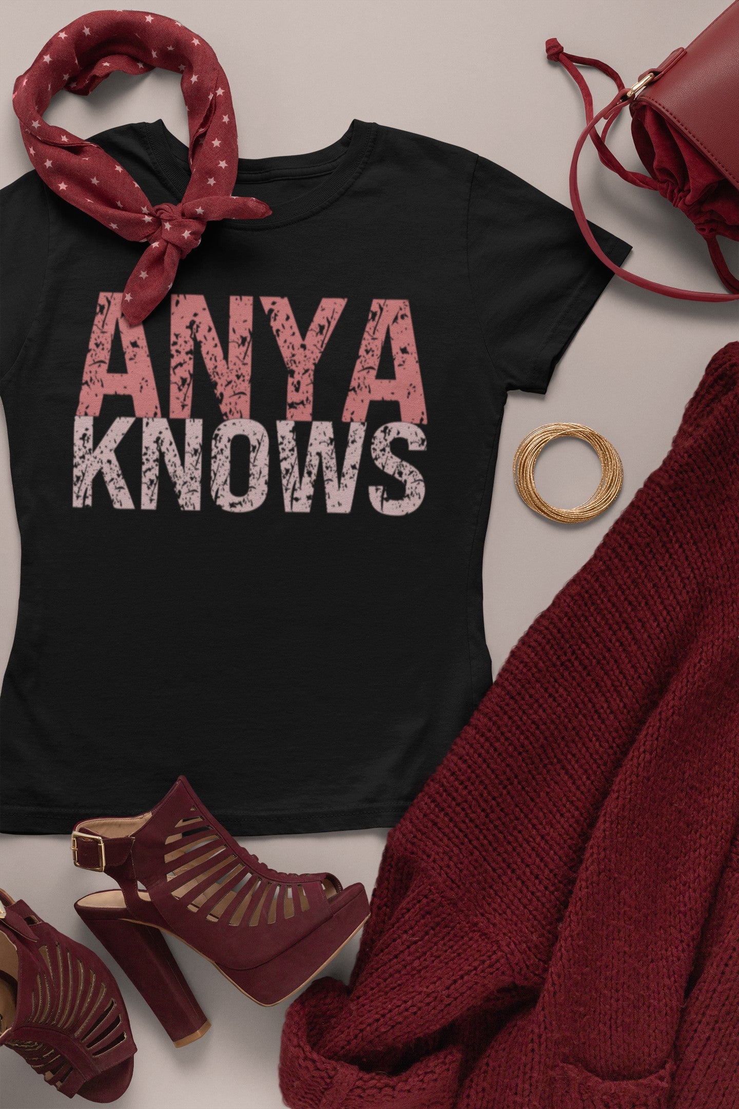 Black t-shirt with 'ANYA KNOWS' text, surrounded by red accessories on a light background