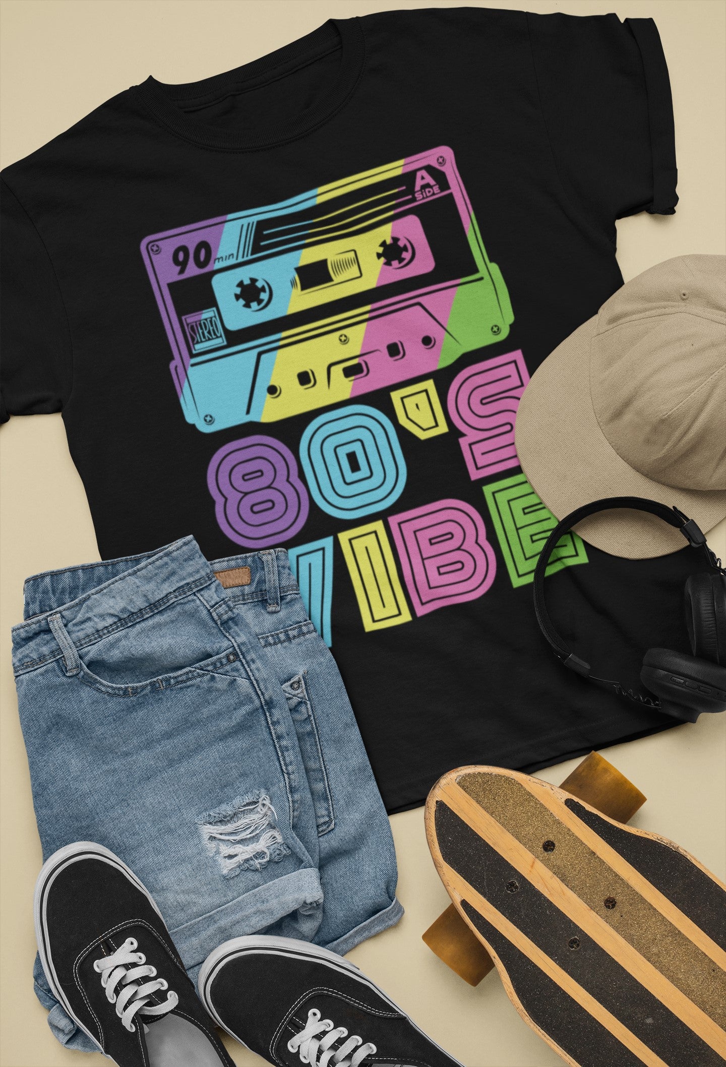 Black t-shirt with colorful cassette tape design, paired with jeans, sneakers, a cap, and skateboard.