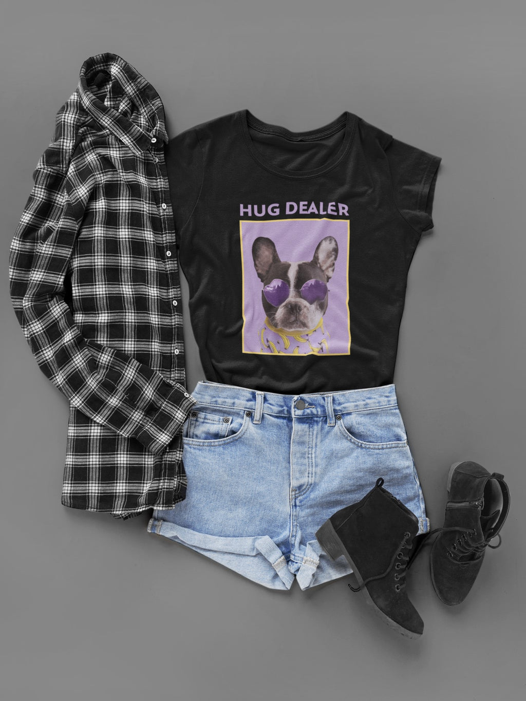 Black t-shirt with 'Hug Dealer' graphic, plaid shirt, denim shorts, and black shoes on a gray background