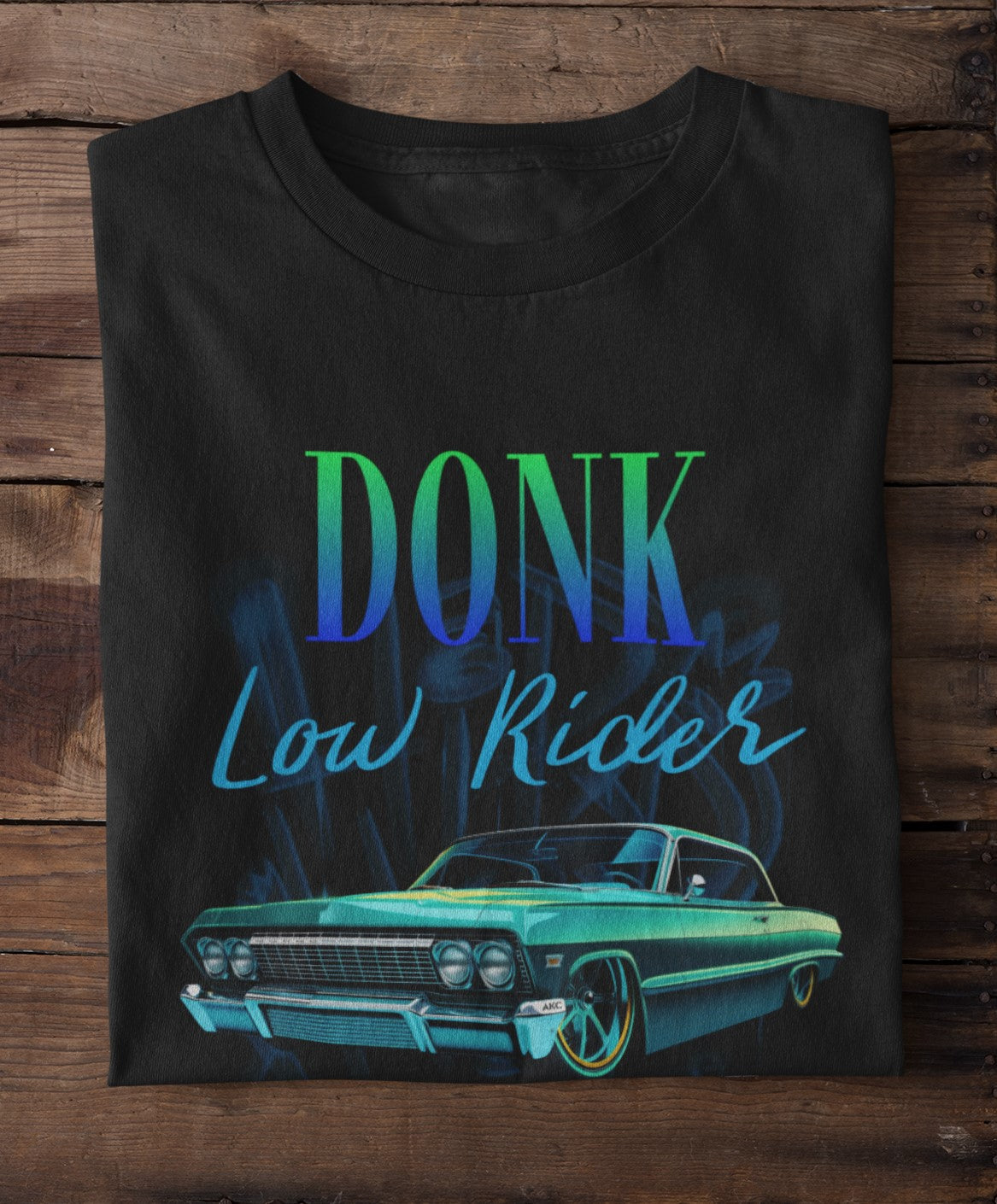 Black t-shirt with 'DONK Low Rider' text and lowrider car graphic on a wooden surface