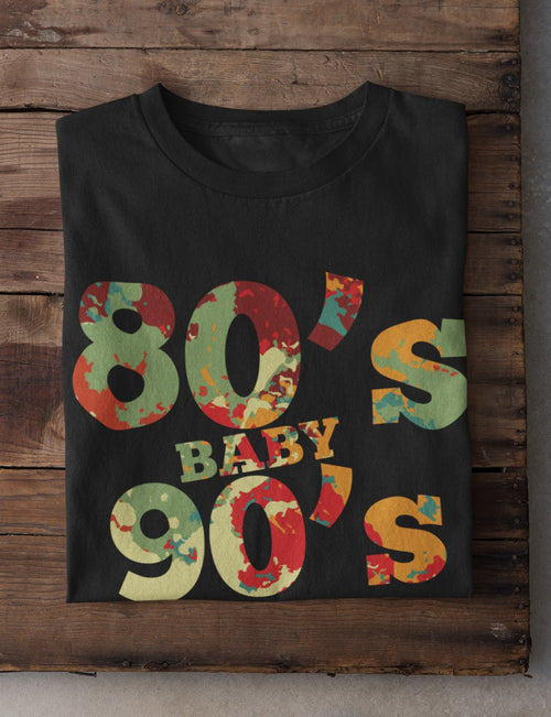 Black t-shirt with colorful '80's Baby 90's' text on a wooden background