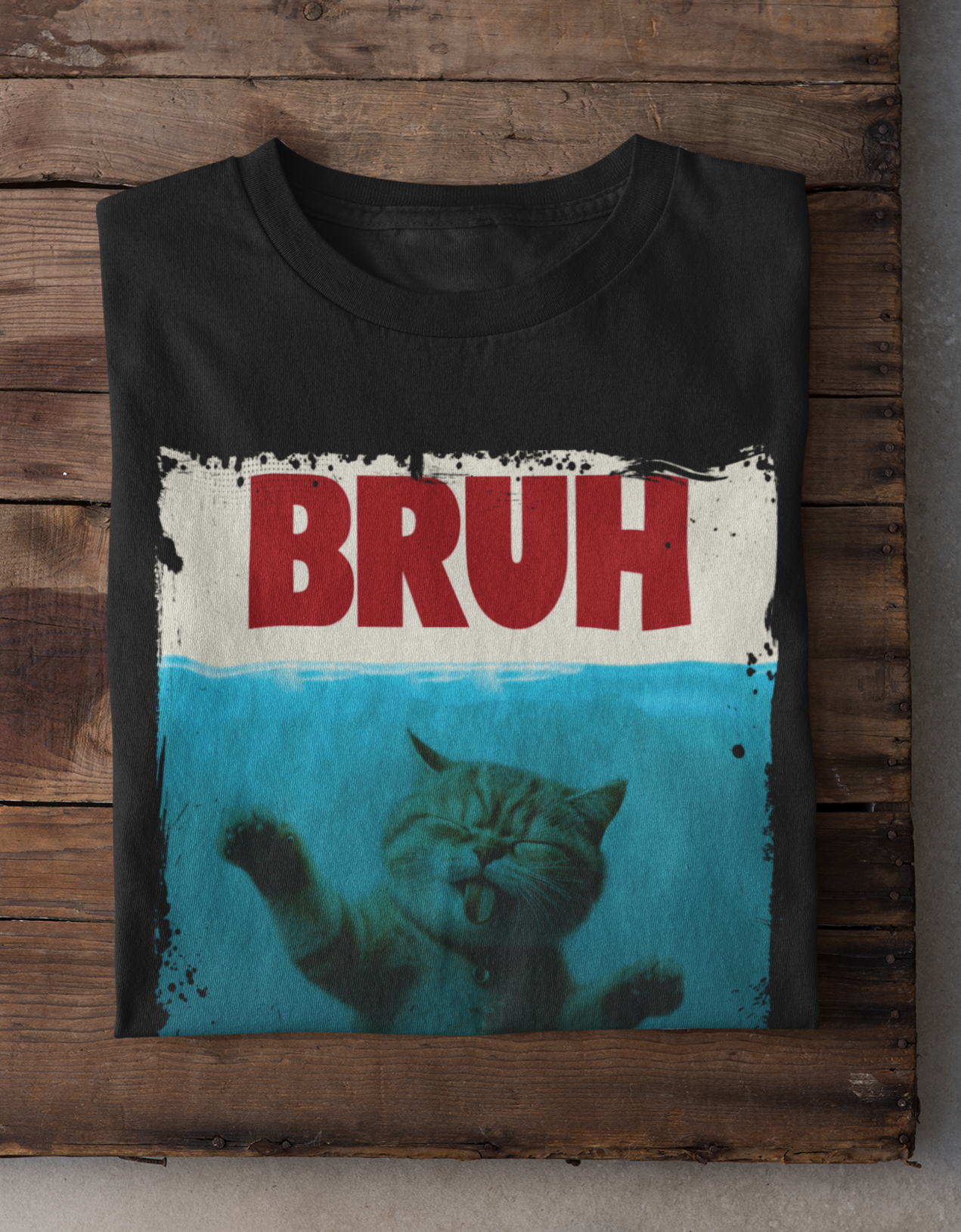 Black t-shirt with 'BRUH' text and cat graphic on a wooden surface