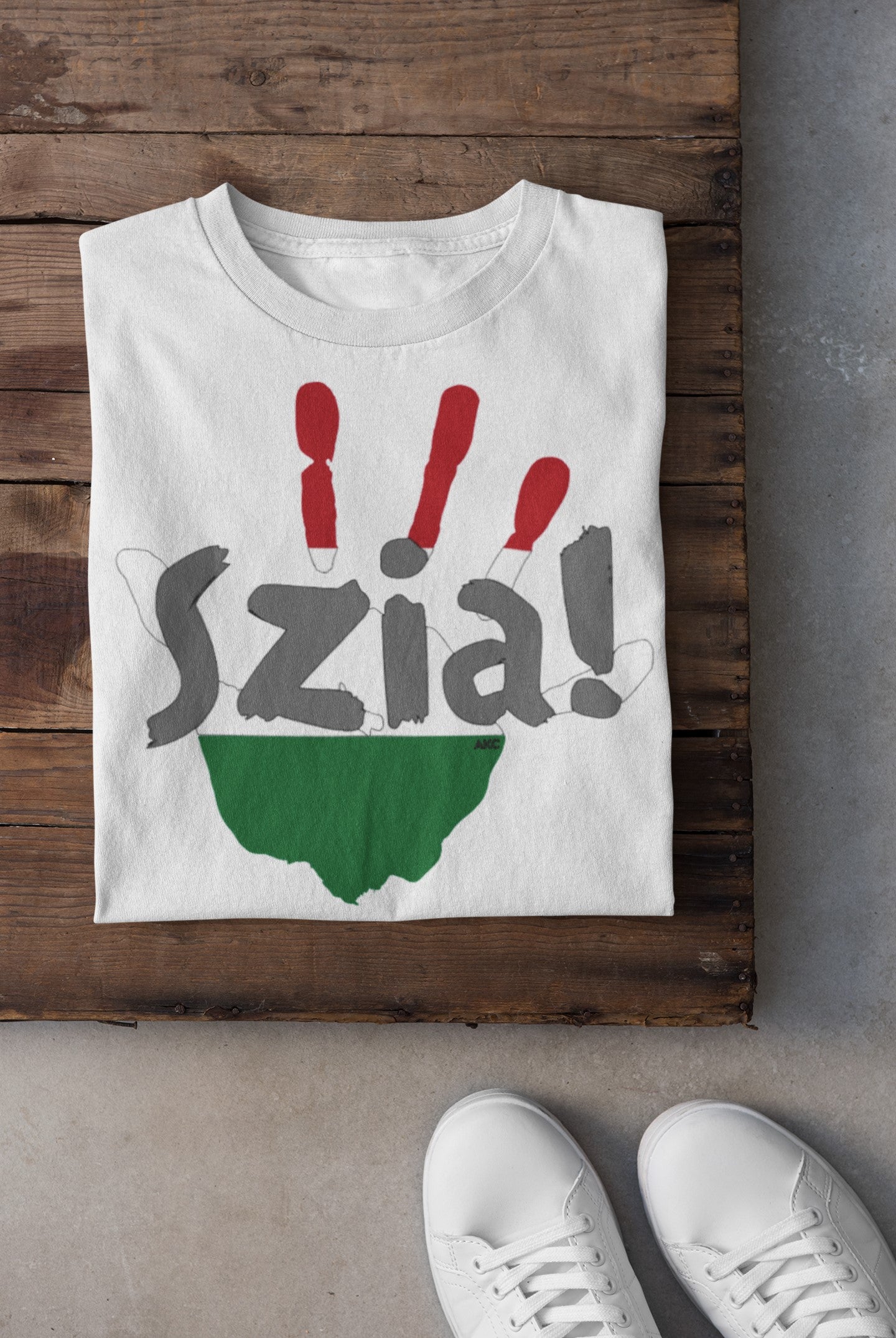 White t-shirt with 'Szia!' design on a wooden surface