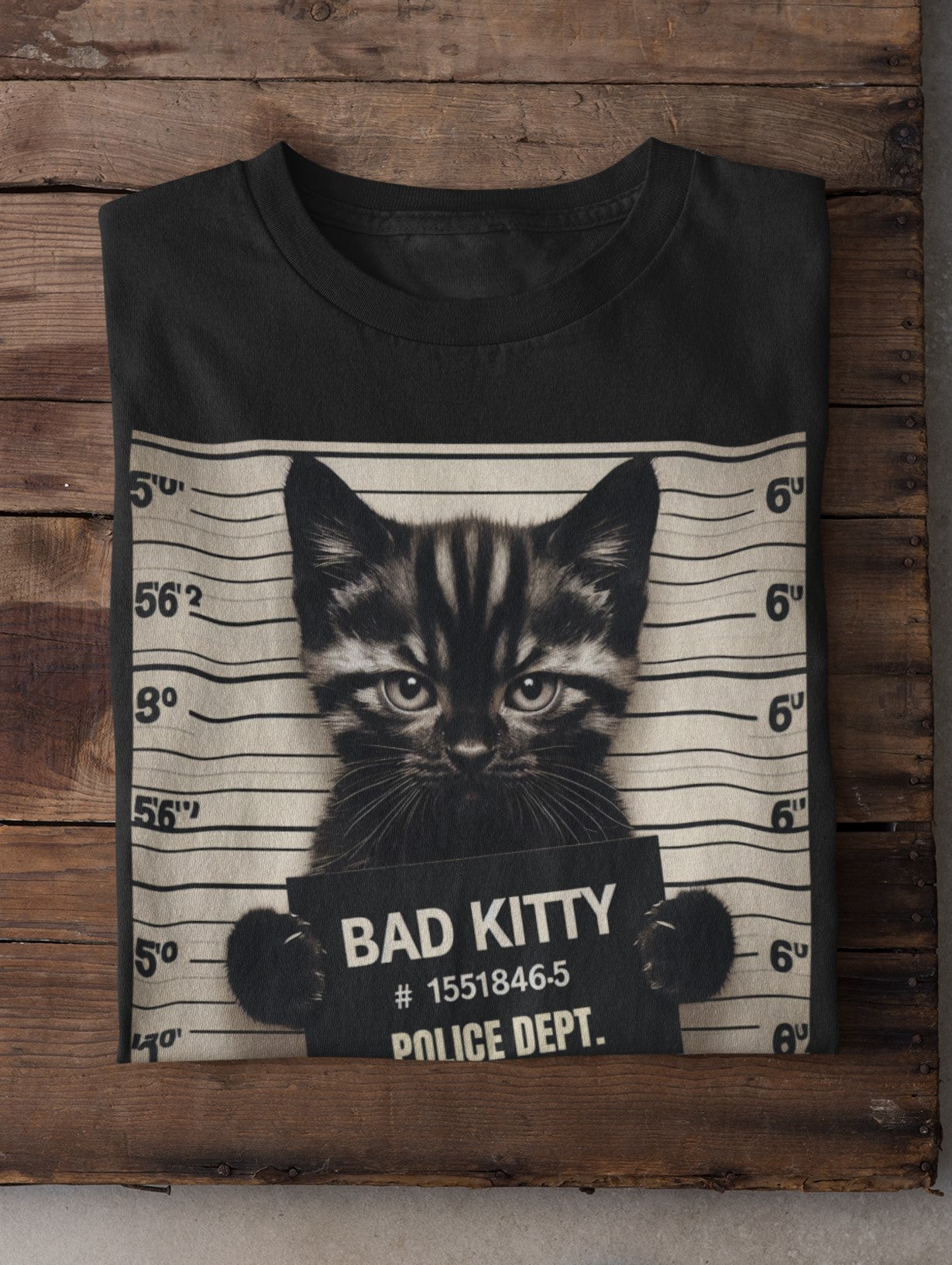 Black t-shirt with a cat mugshot design on a wooden background