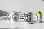 Two white ceramic mugs on a white tabletop in a styled studio setting. The left mug shows a circular black graphic of a hand making the peace sign with the text 'DON'T RIDE ON THE CRAZY TRAIN I DRIVE IT'.
