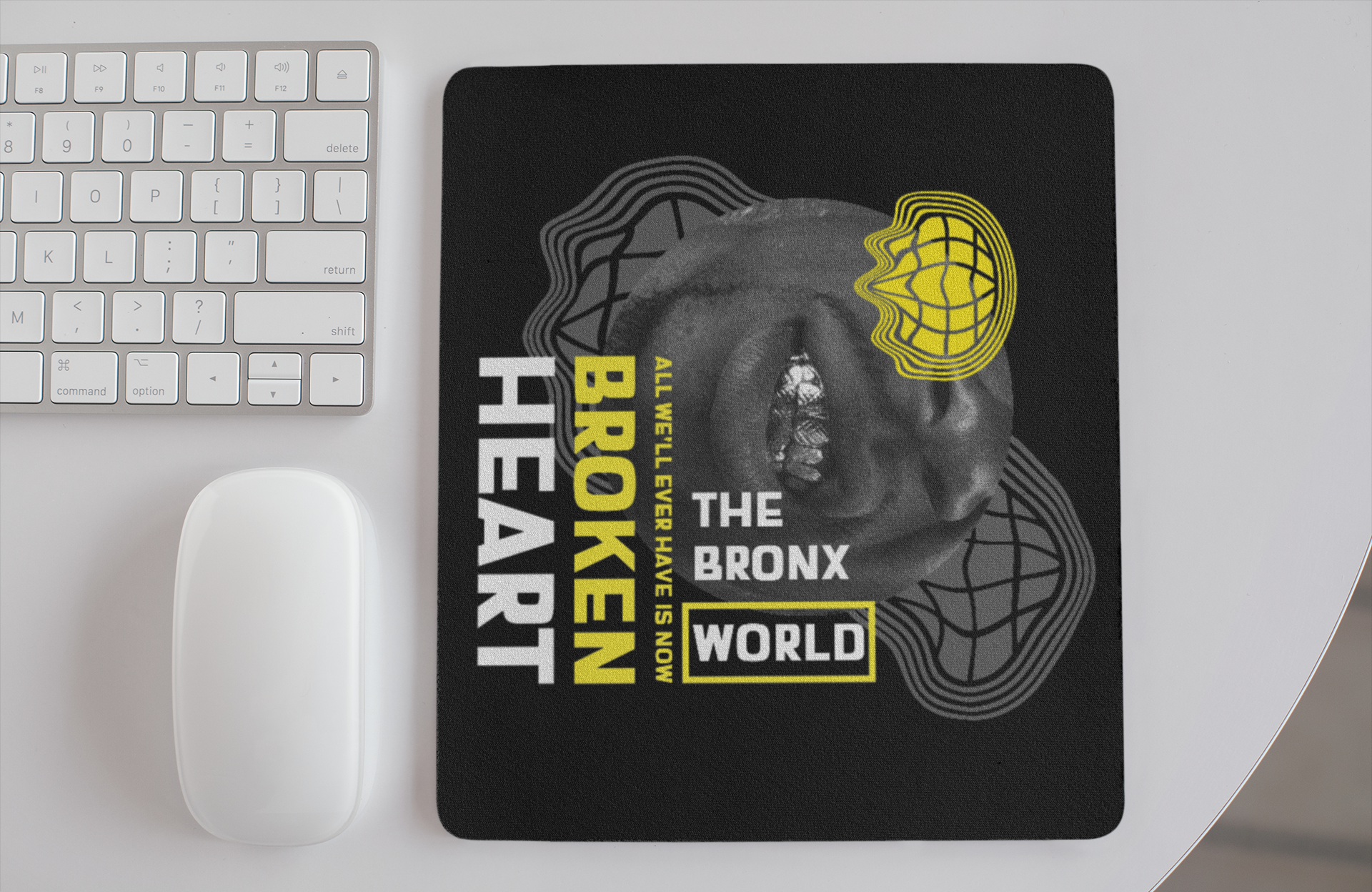 Mouse pad with 'Broken Heart, The Bronx World' design on a desk with keyboard and mouse.