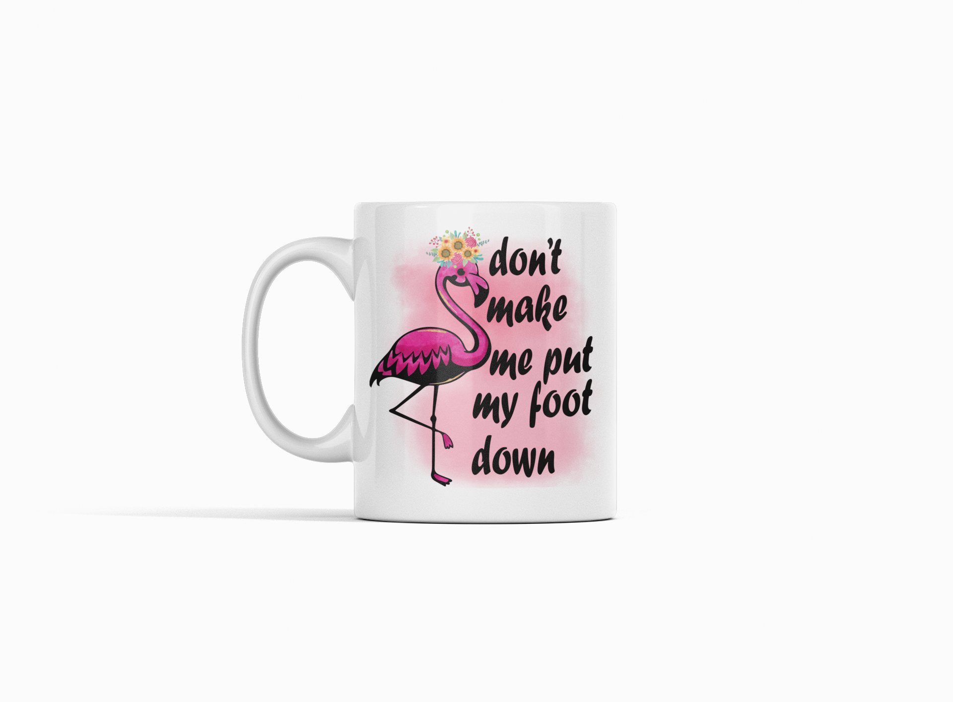 A white ceramic mug featuring a pink flamingo illustration with a flower crown and the text 'don't make me put my foot down' in black script, shown on a clean white background.