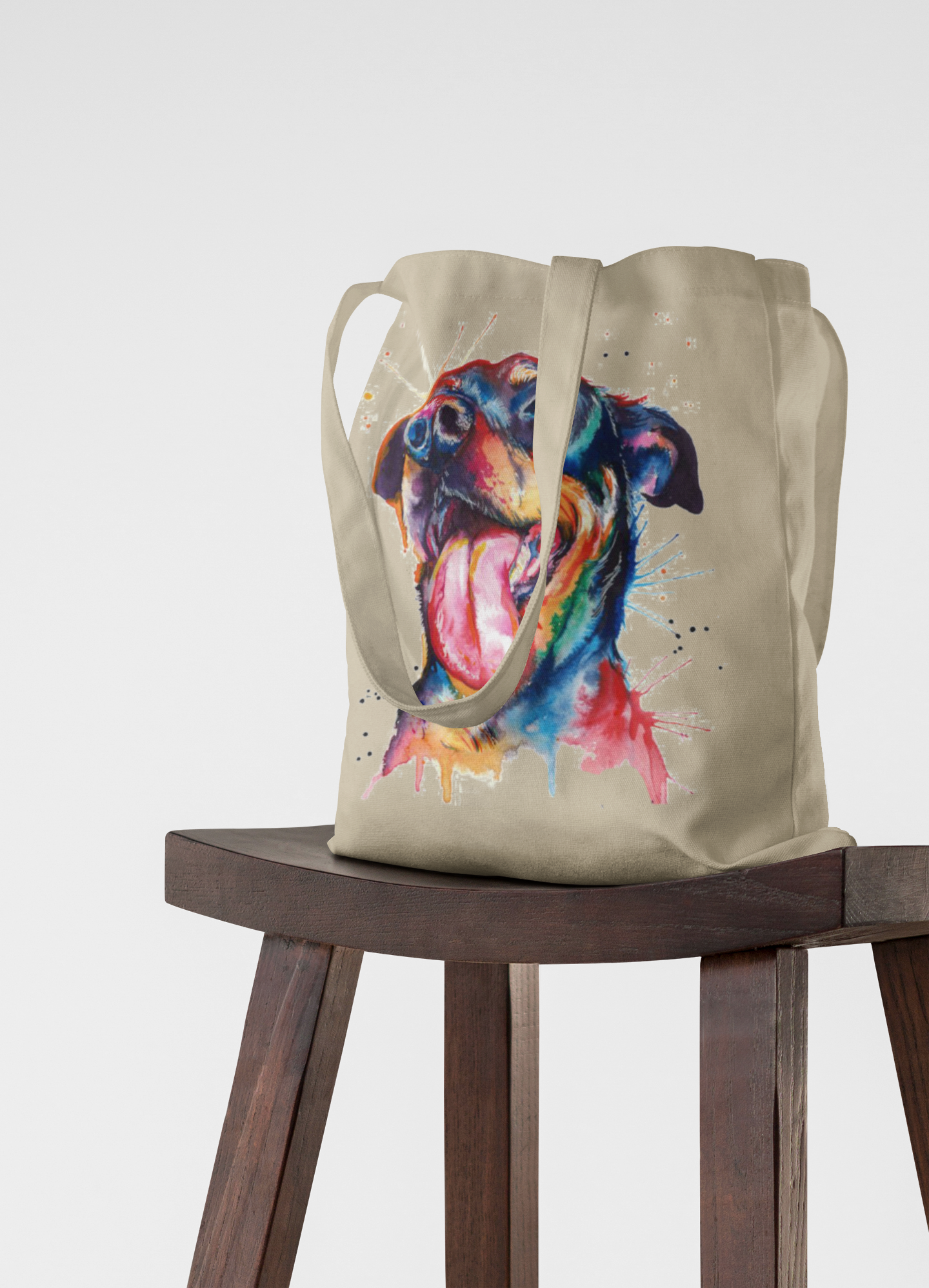 Tote bag with a colorful dog illustration on a wooden stool against a white background