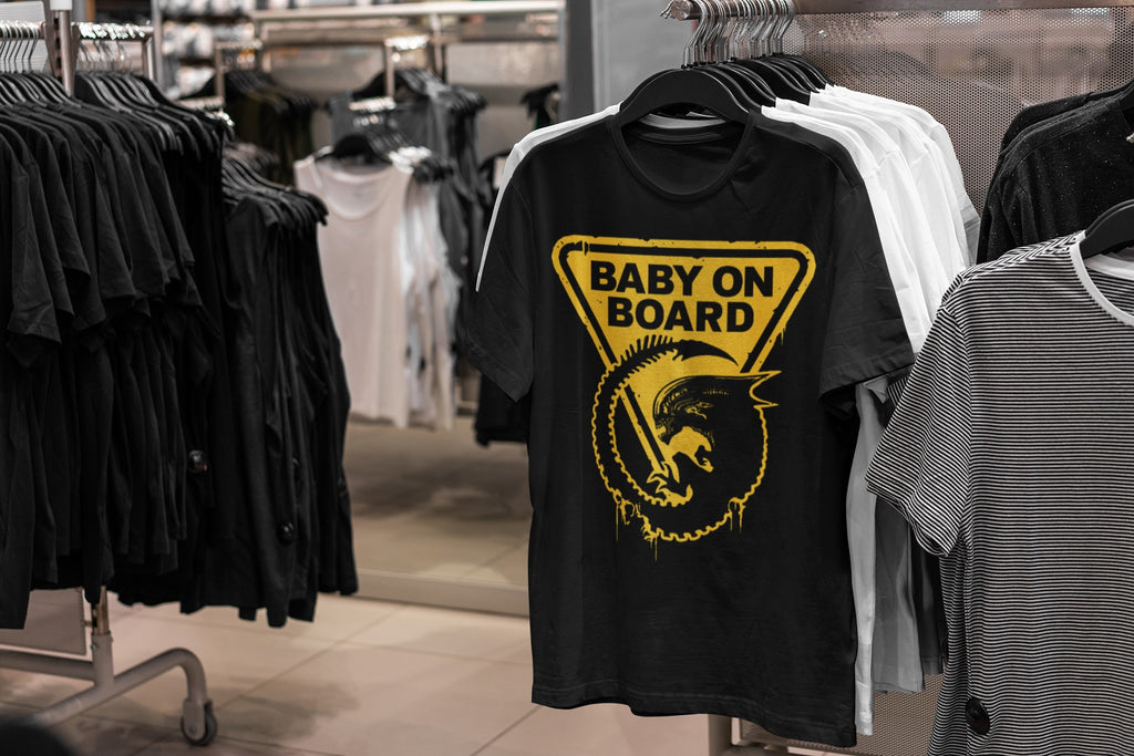Black t-shirt with yellow graphic and 'Baby on Board' text in a clothing store.