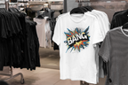 A white short-sleeve graphic T-shirt hanging on a black hanger in a clothing store, featuring a colorful comic-style explosion graphic with the word 'BANG' in white outlined in black.