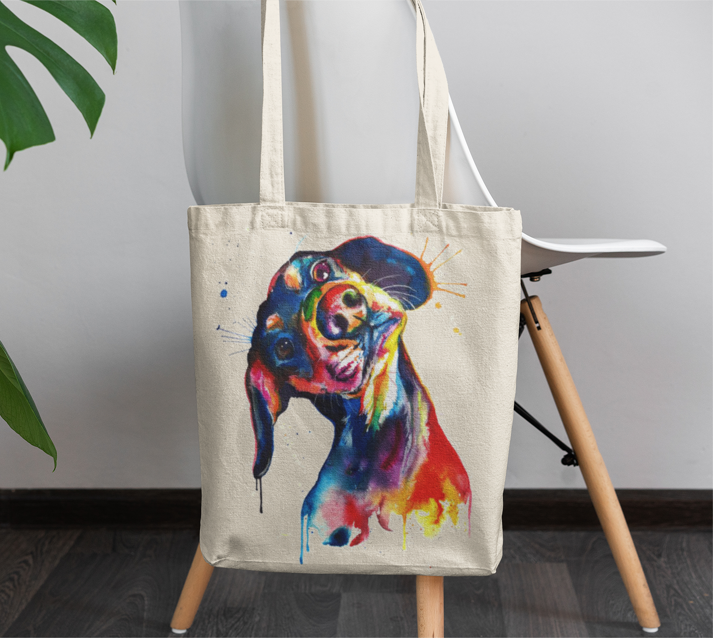 Tote bag with a colorful dog illustration on a chair against a plain wall.