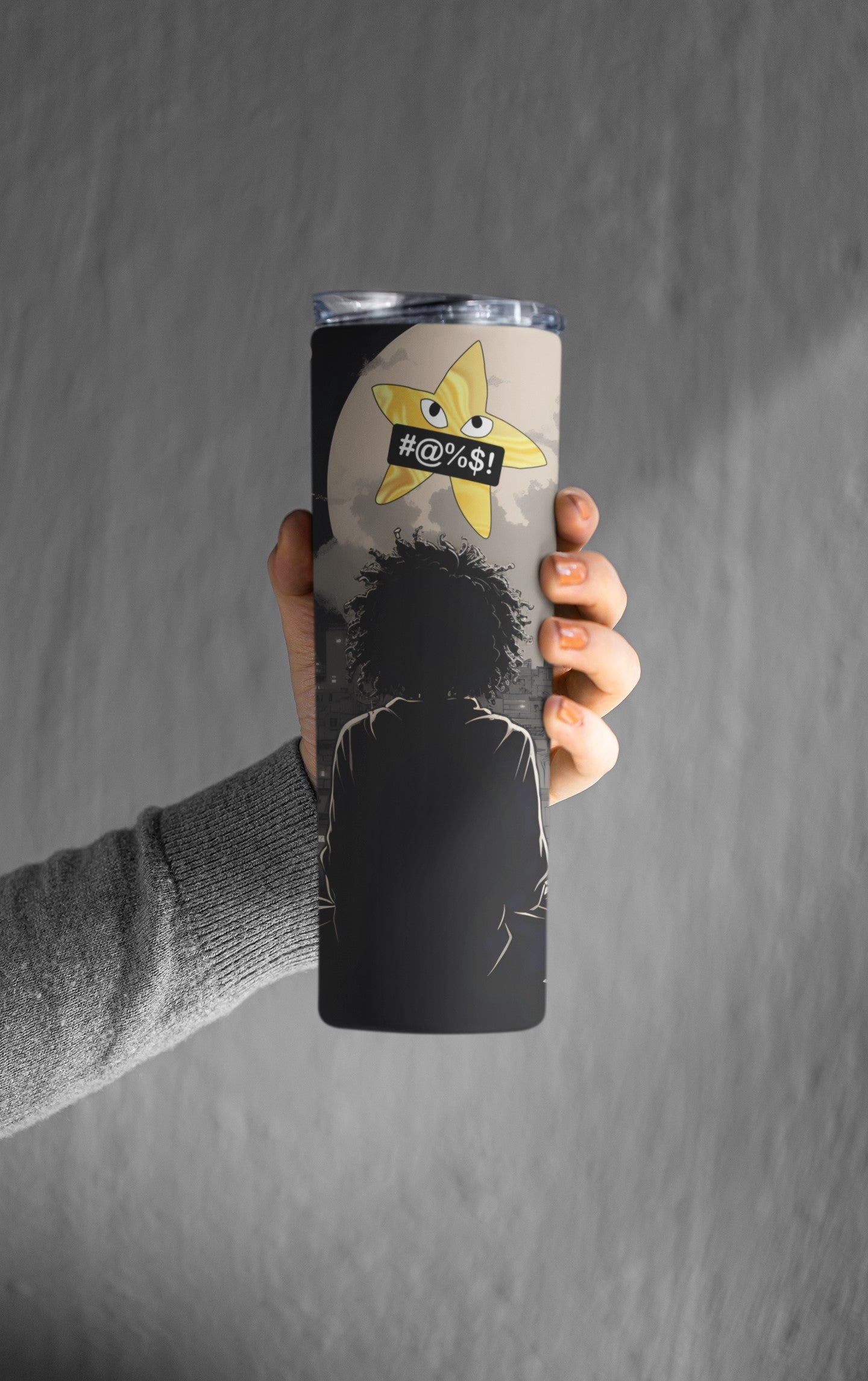 Person holding a tumbler with a graphic design on a gray background