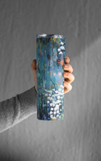 Hand holding a tumbler with a floral design against a gray background