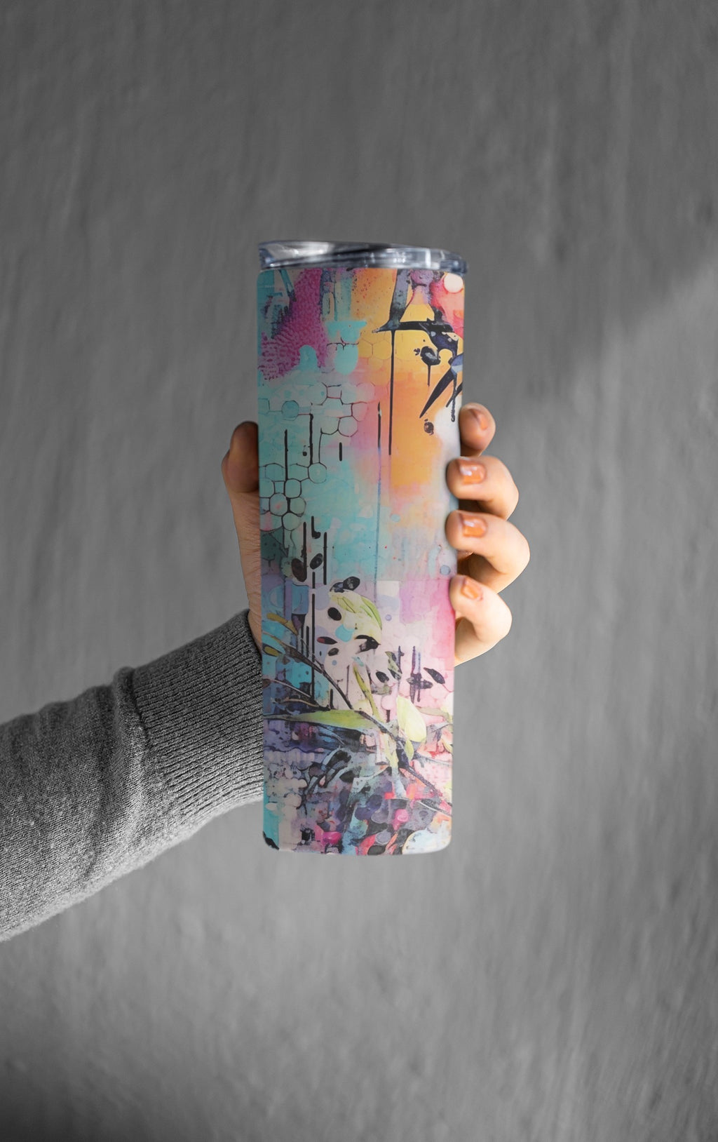 Hand holding a colorful water bottle against a gray background