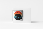 A square white product box with a die-cut window displaying a circular graphic of a black elephant silhouette against a retro sunset background with birds.