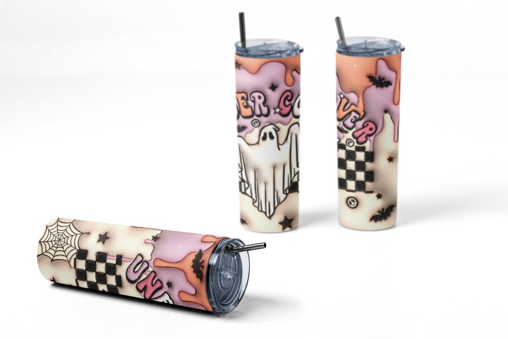 Three views of a Halloween-themed skinny tumbler with a clear lid and straw. The design features a cream background with pink ghostly drips, black spiderwebs, black-and-white checkered squares, black bats, and a white ghost illustration.