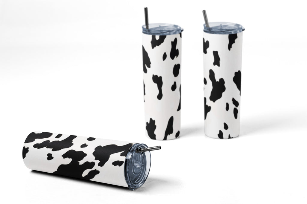Three cow print tumblers with straws on a white background