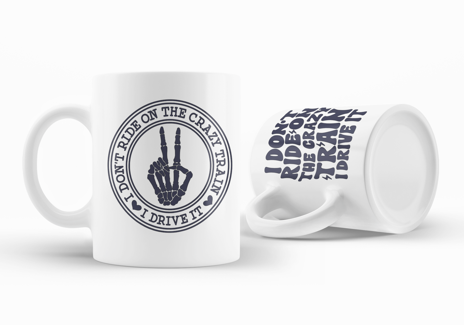 Two white ceramic mugs with dark navy blue printed graphics on a clean white background. One mug is upright and shows a circular graphic of a skeleton hand making a peace sign with the text 'I DON'T RIDE ON THE CRAZY TRAIN I DRIVE IT'.