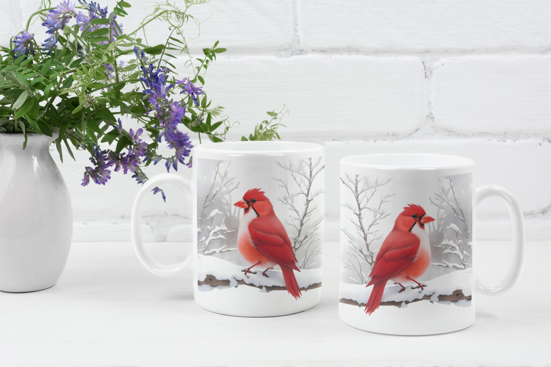Two mugs with red cardinal designs on a white surface with a vase of flowers.