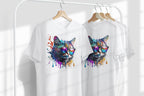 Two white t-shirts with colorful cat designs on hangers against a white background