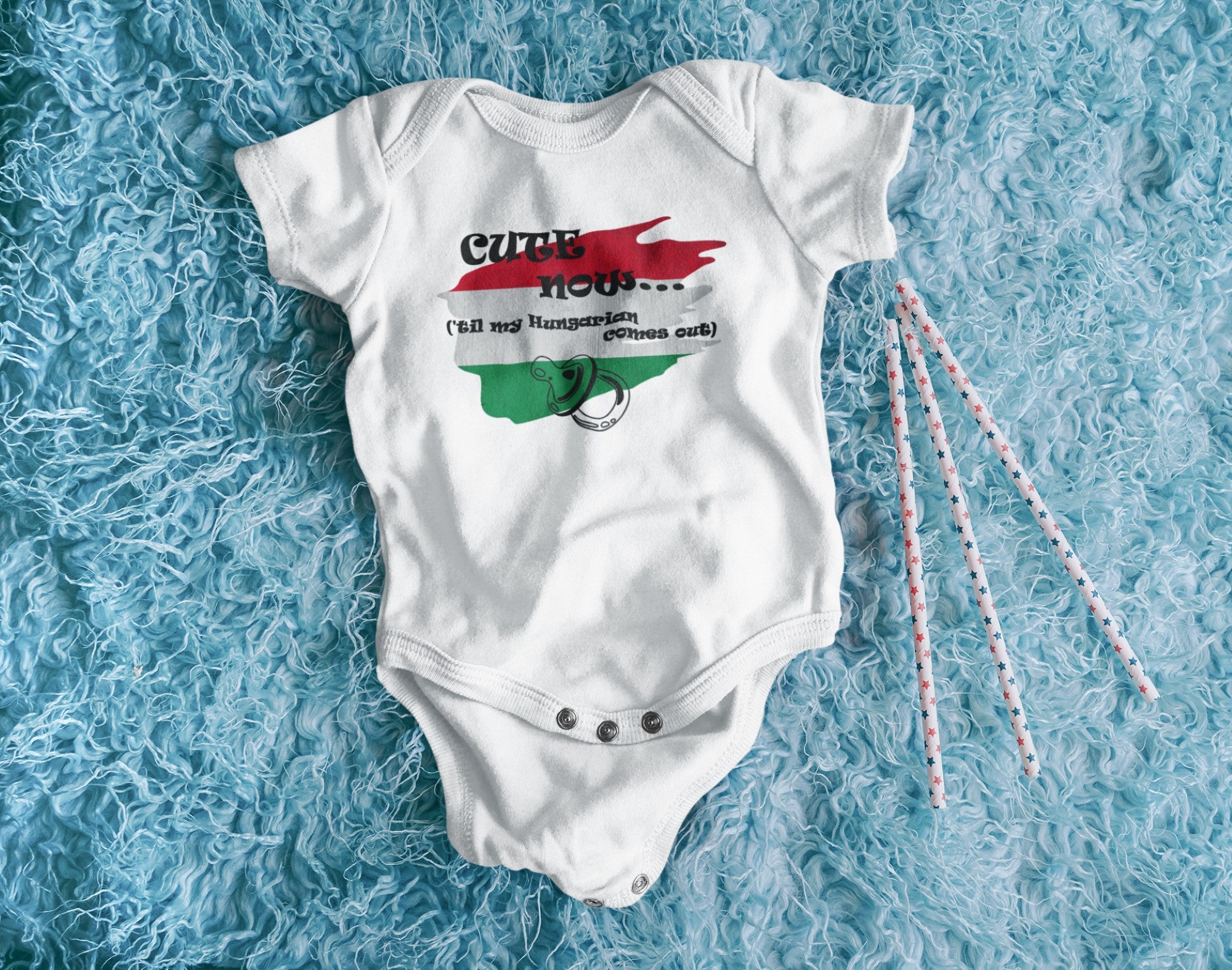 White baby onesie with colorful design on a blue textured surface