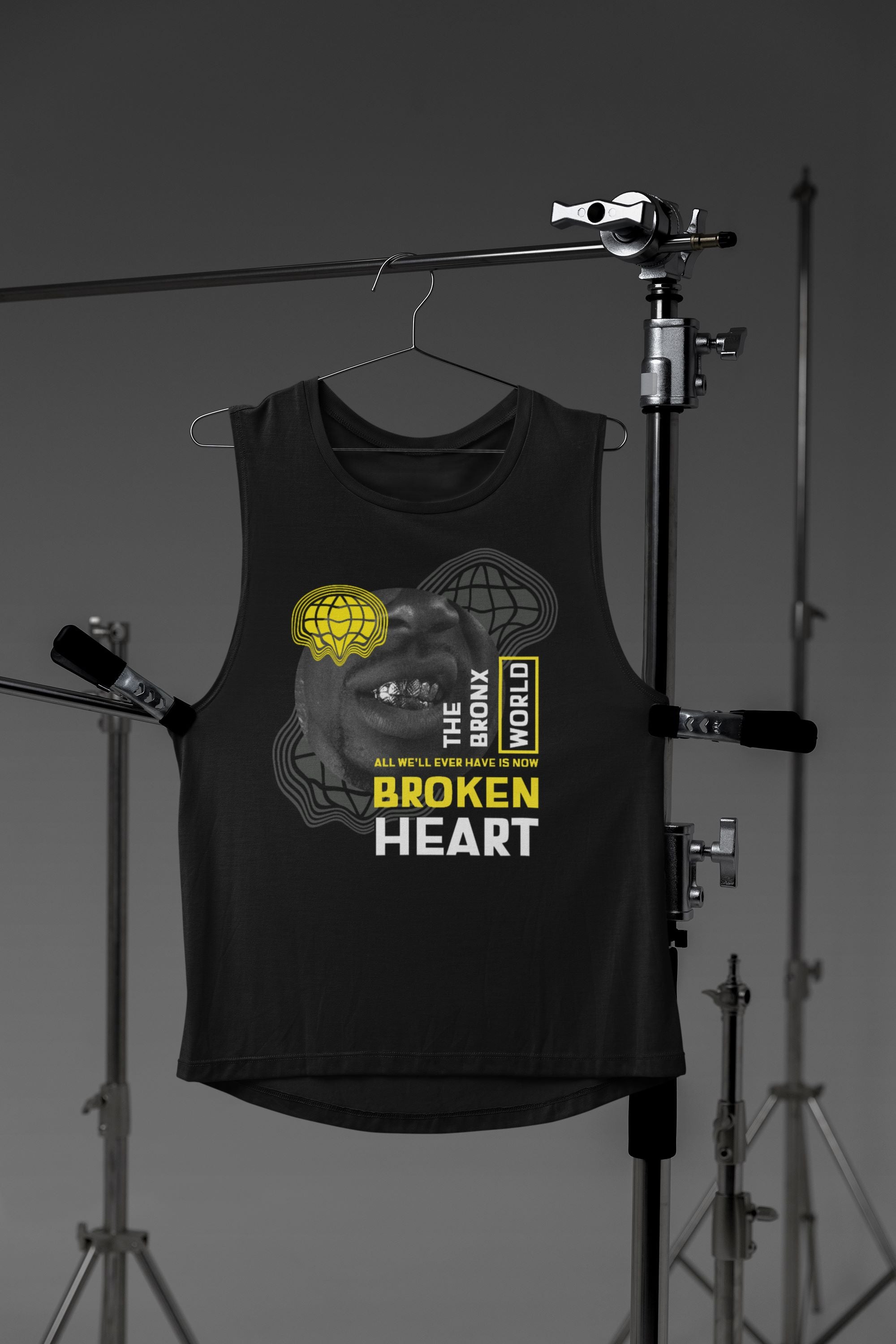 Black sleeveless shirt with graphic design on a hanger against a gray studio background