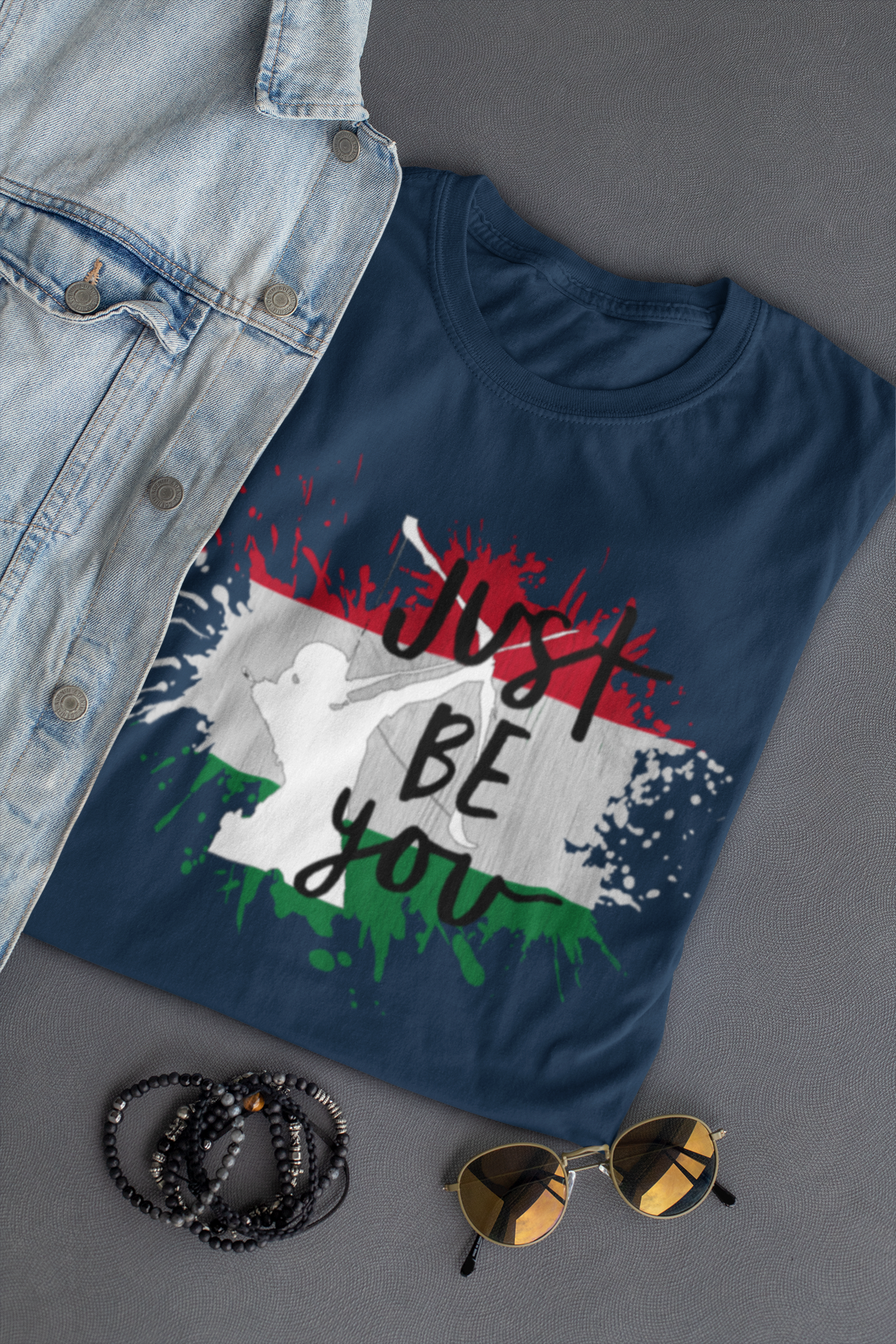 Blue t-shirt with graphic design and accessories on a gray surface