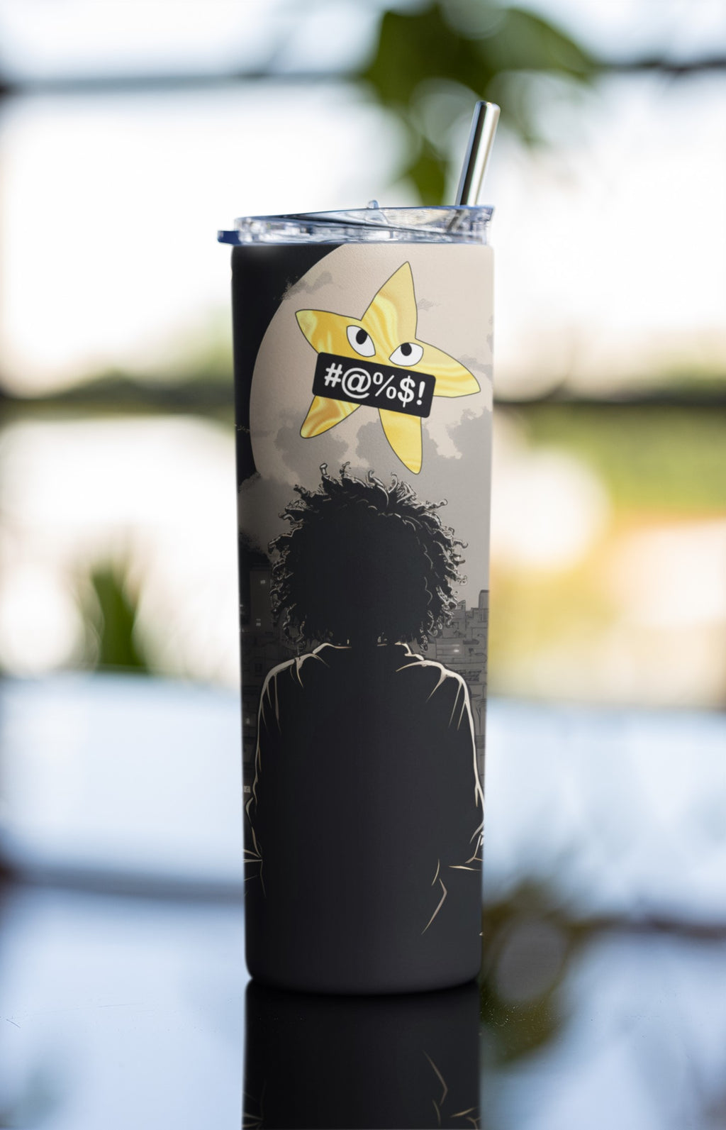 Tumbler with a graphic design of a silhouette and a star-shaped sticker with text, outdoors.