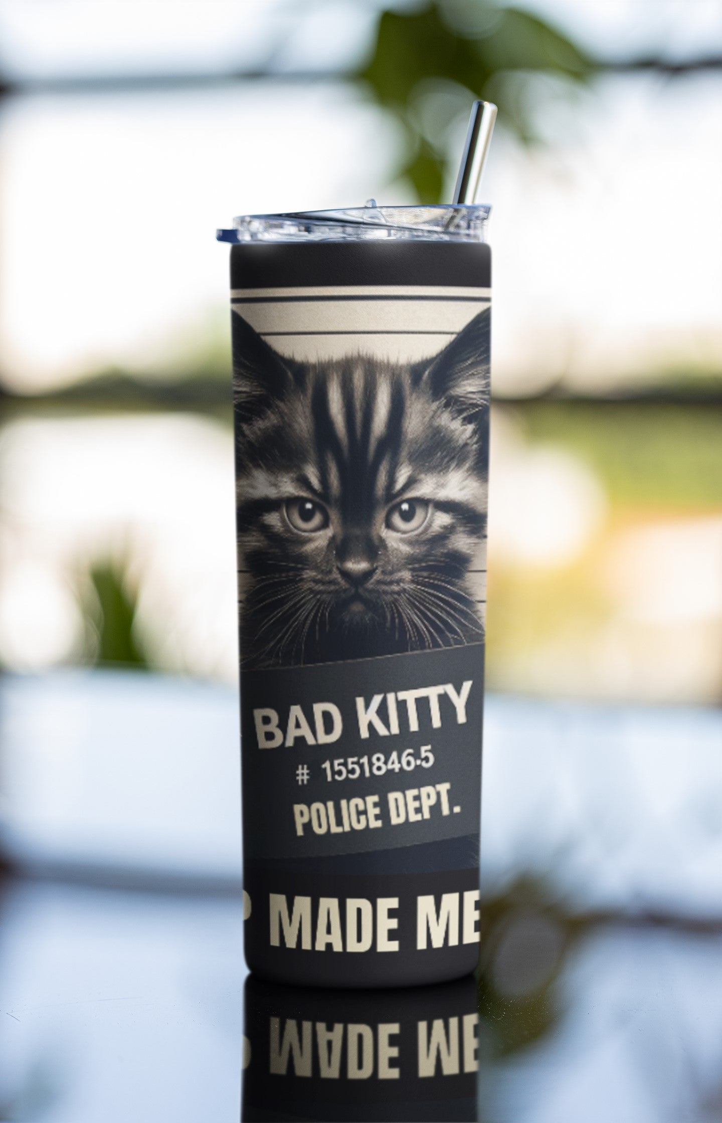 Tumbler with a cat design and text on a blurred outdoor background